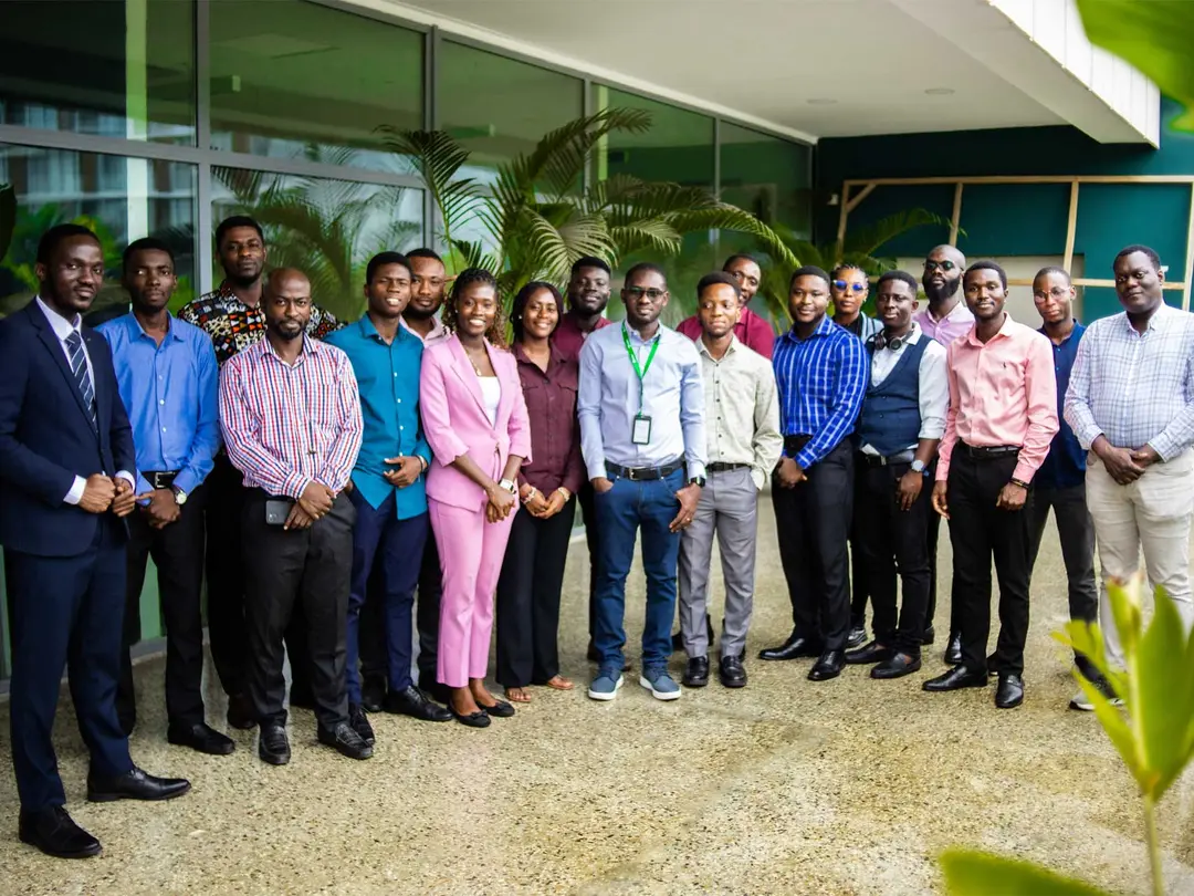A group of individuals is standing in a line outdoors for a group photo.